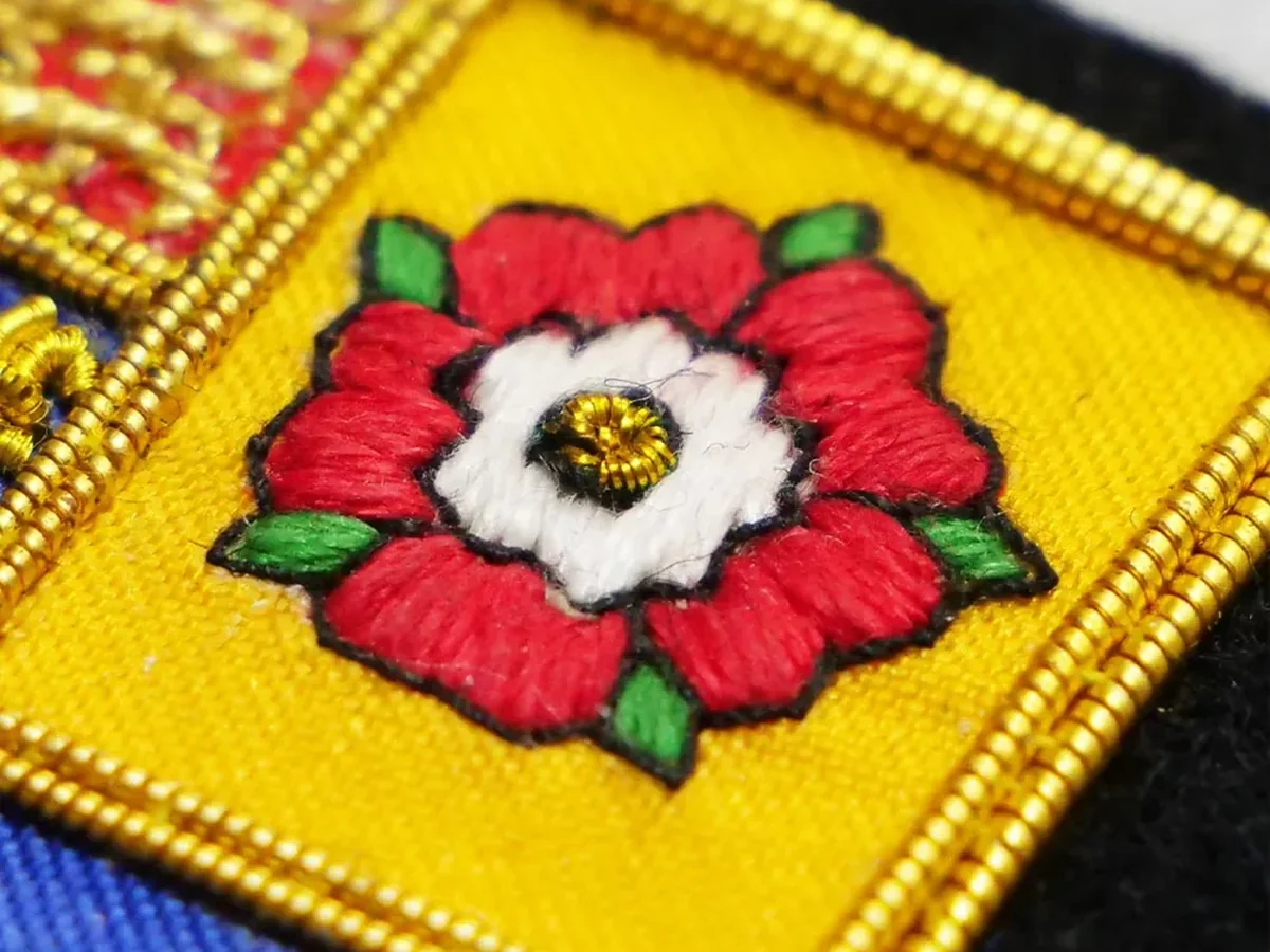 Close-up of hand-sewn bullion wire embroidery on a finished badge
